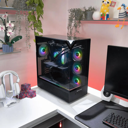 Gaming PC with RGB fans and liquid cooling in black case on white corner desk with headset and monitor
