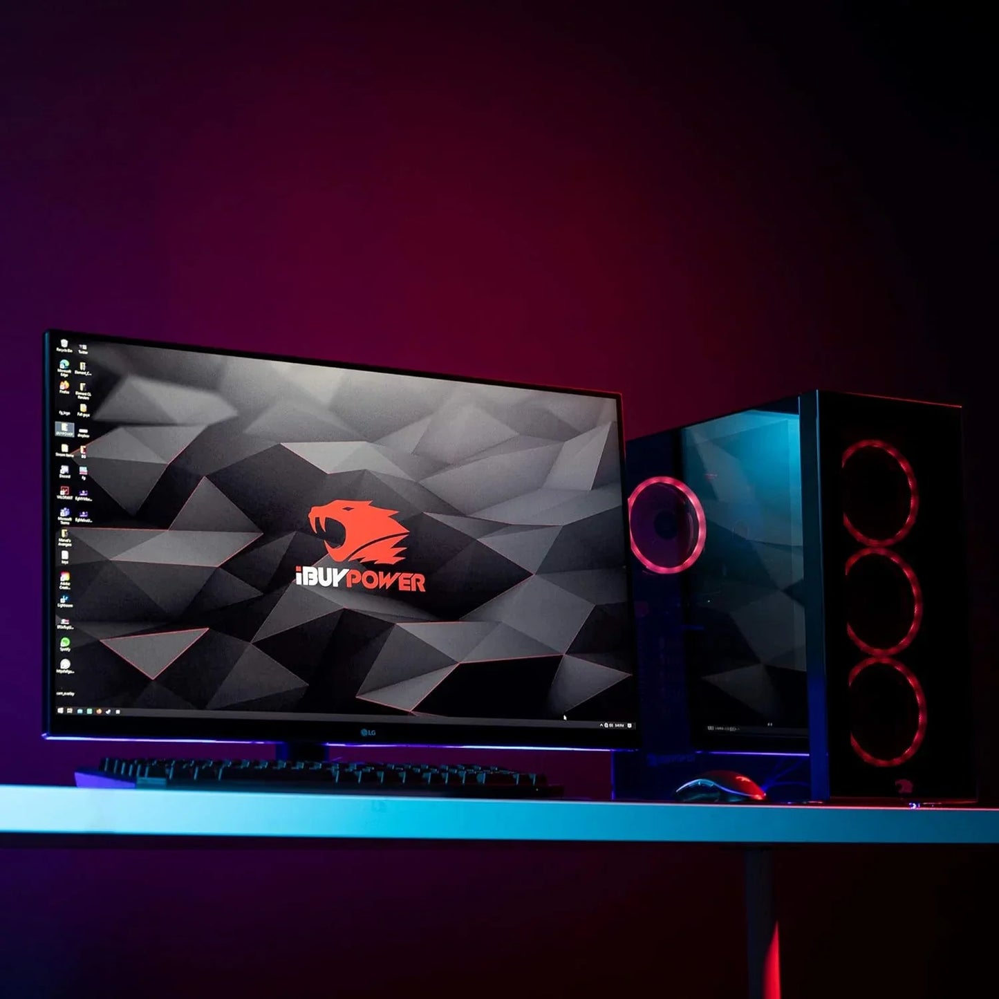 Gaming PC setup with LG monitor displaying iBUYPOWER logo, RGB-lit desktop tower, keyboard, and mouse on white desk