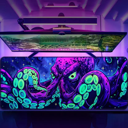 RGB gaming desk setup featuring a large mousepad with neon purple and green octopus design under a mounted widescreen monitor