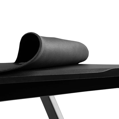 Black rolled gaming mouse pad on a sleek black desk with metal legs