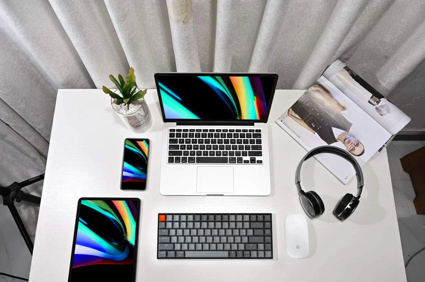 Minimal modern gaming desk setup with laptop, keyboard, mouse, tablet, phone, and headset
