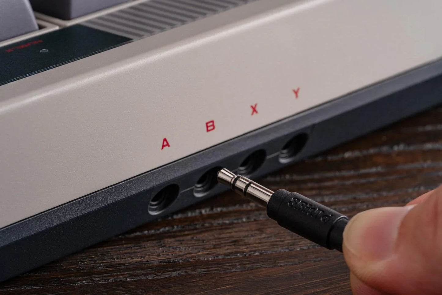 Close-up of plugging an audio jack into retro gaming console with ABXY controller ports
