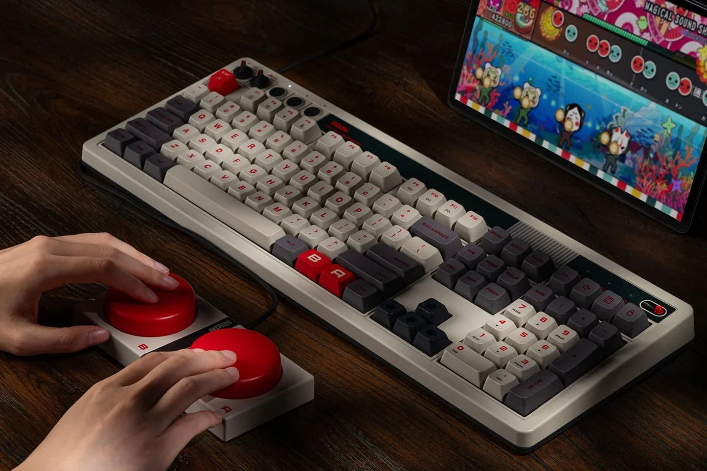 Retro mechanical keyboard and arcade game controller with red buttons on a wooden desk