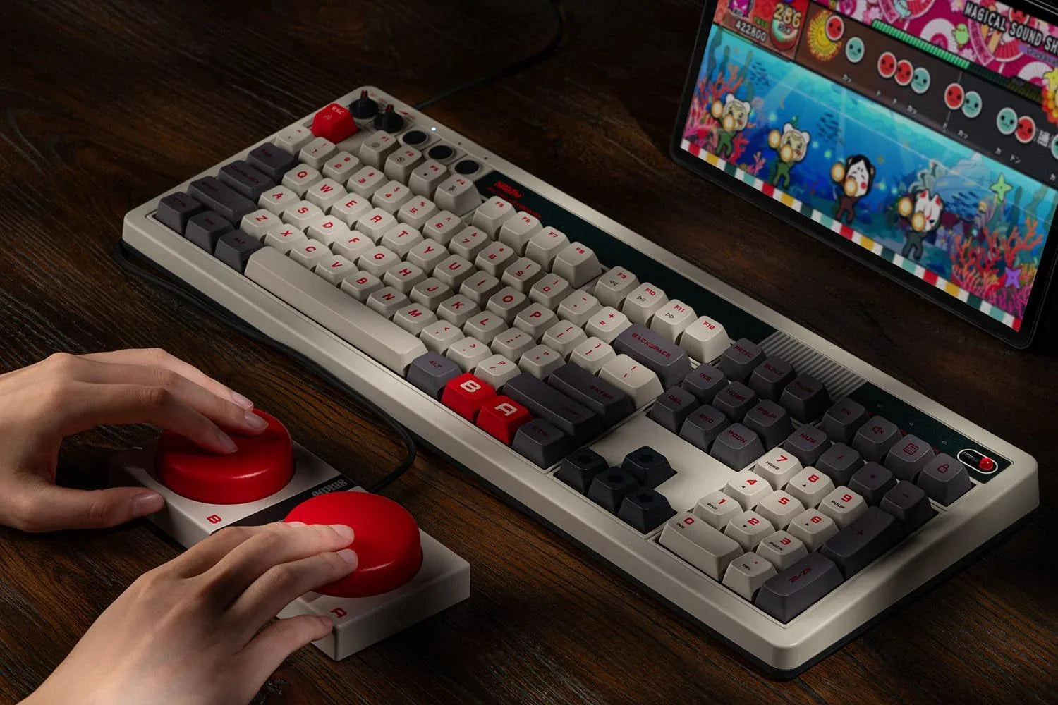 Retro mechanical keyboard and arcade game controller with red buttons on a wooden desk