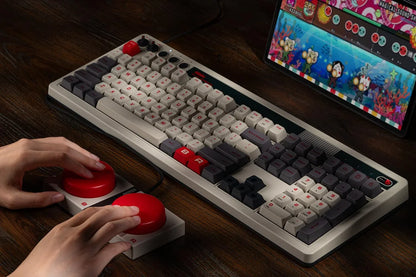 Retro mechanical keyboard and arcade game controller with red buttons on a wooden desk