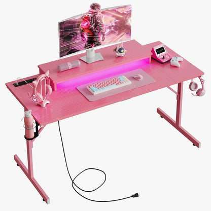 Pink gaming desk setup with curved monitor, pastel mechanical keyboard, pink mouse, LED lighting, headphones, and gaming accessories