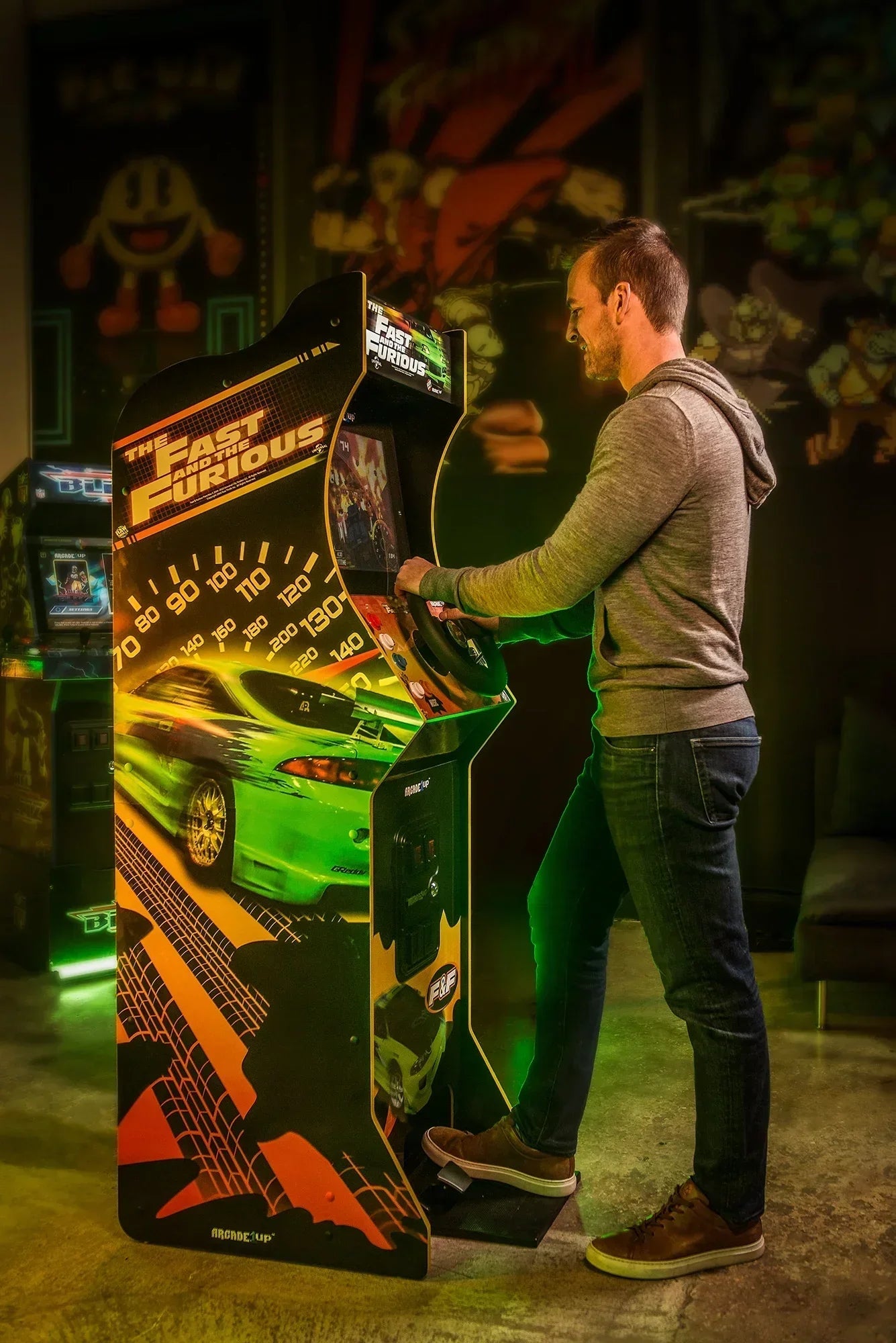 Man playing The Fast and the Furious arcade racing game in a retro gaming room with neon lights