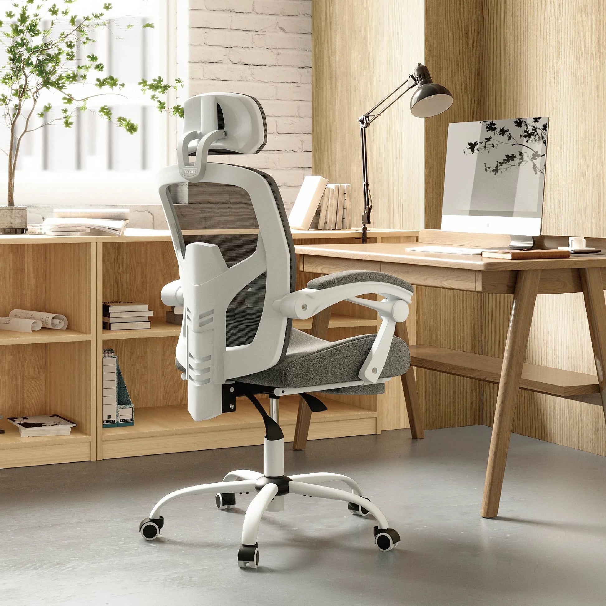 White ergonomic office chair with mesh back, headrest, and adjustable arms at a wooden desk setup
