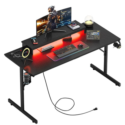 Black gaming desk with RGB keyboard, curved monitor, ring light, and headphone hook
