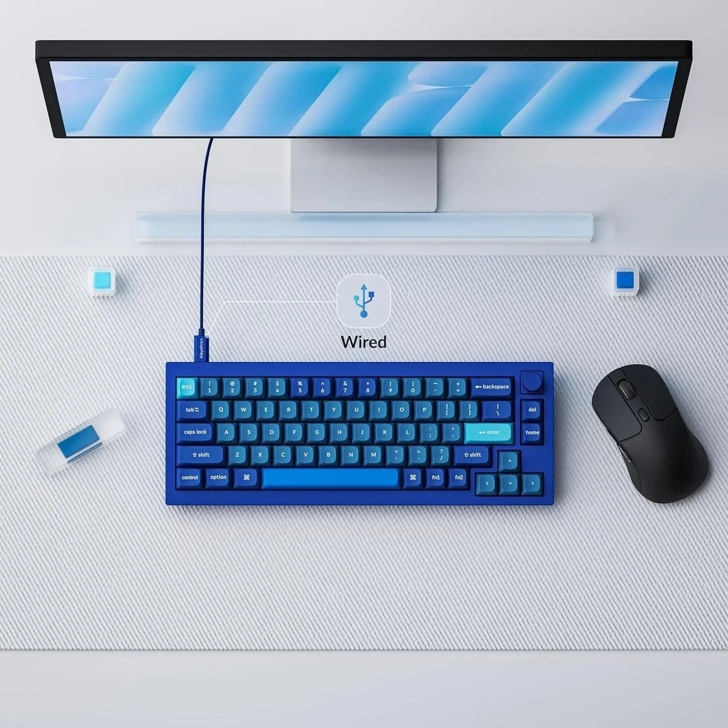 Blue wired gaming keyboard, black mouse, and monitor on a modern Byte Style desk setup.