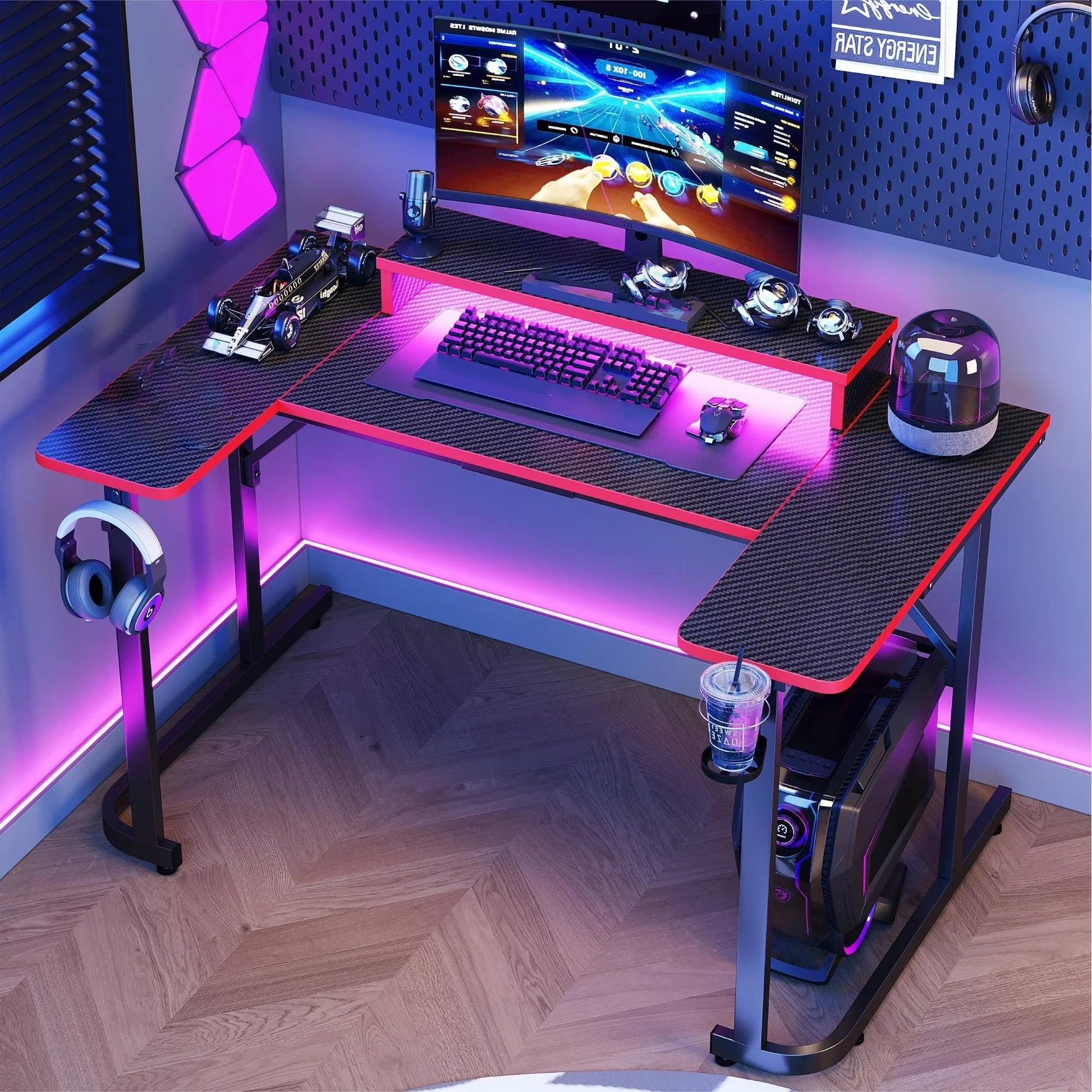 L-shaped 51-inch gaming desk with carbon fiber texture, LED lighting, curved monitor, keyboard, mouse, headphone hanger, and cup holder