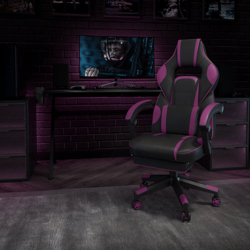 Pink and black gaming chair in a dark, moody setup with monitor, keyboard, and controller on desk against brick wall.