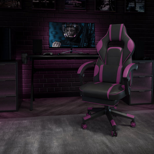 Pink and black gaming chair in a dark, moody setup with monitor, keyboard, and controller on desk against brick wall.