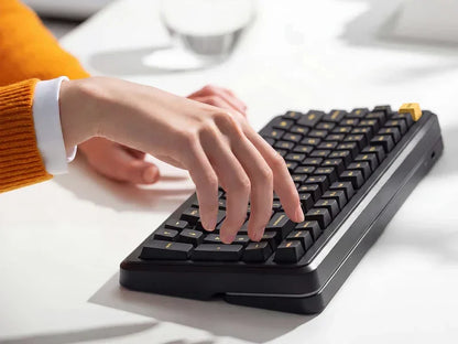Person typing on black mechanical gaming keyboard with gold accents, retro 8-bit style
