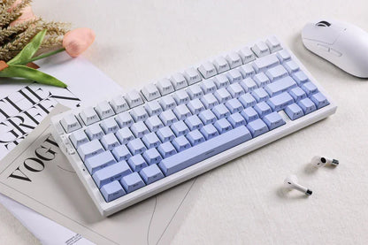 Pastel purple and white mechanical keyboard with wireless earbuds and mouse on desk