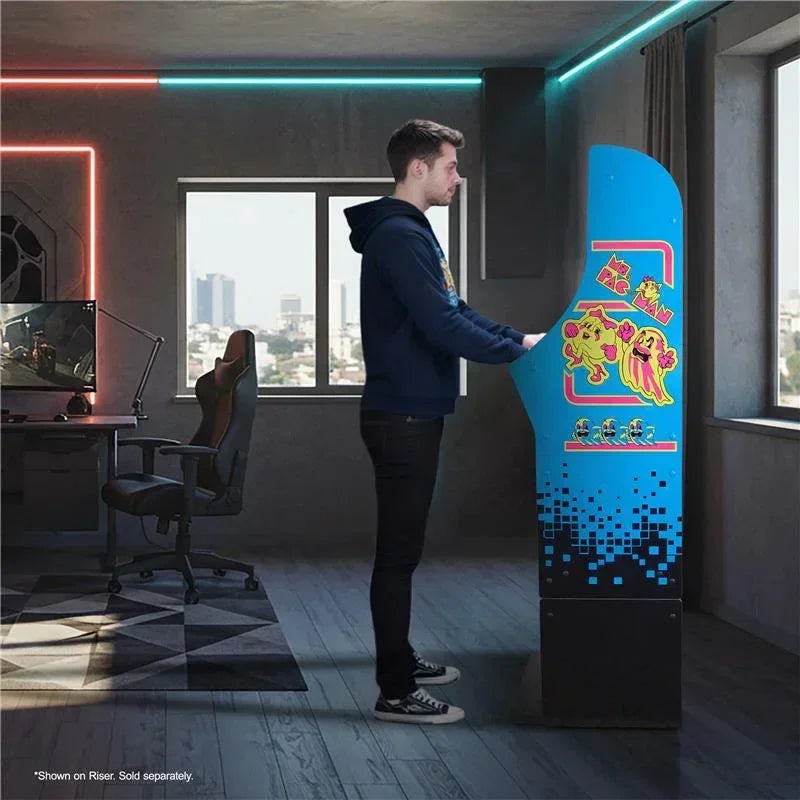 Man playing retro Ms. Pac-Man arcade cabinet in a modern gaming room with RGB lights.