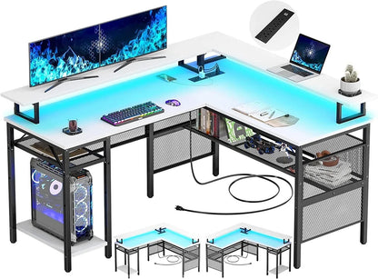 L-shaped gaming and office desk with LED lights, dual monitors, computer tower, keyboard, mouse, laptop, and shelves