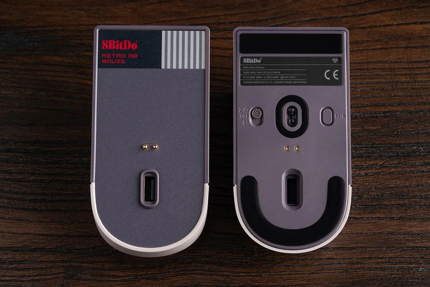 Bottom view of two retro-style 8BitDo wireless gaming mice on wooden surface