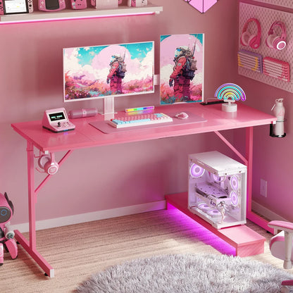 Pink gaming desk setup with dual monitors, colorful keyboard, headset, PC with purple lights, and space-themed astronaut wallpaper