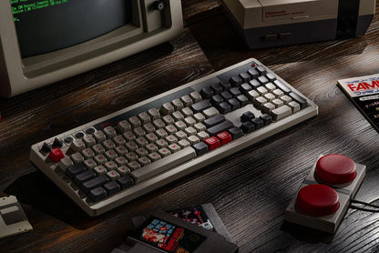 Retro 8-bit gaming mechanical keyboard with vintage PC, NES console, and game cartridges.