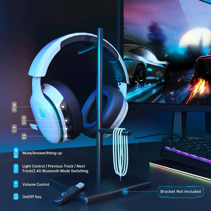 White gaming headphones with controls on ear cup on black stand next to RGB keyboard and racing game on monitor