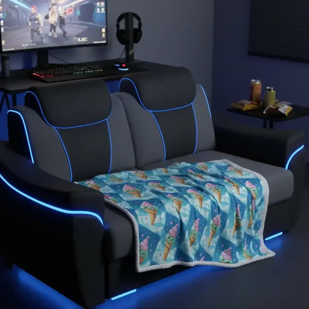 Black and gray gaming sofa with blue LED lights and ice cream cone patterned blanket in front of a gaming desk