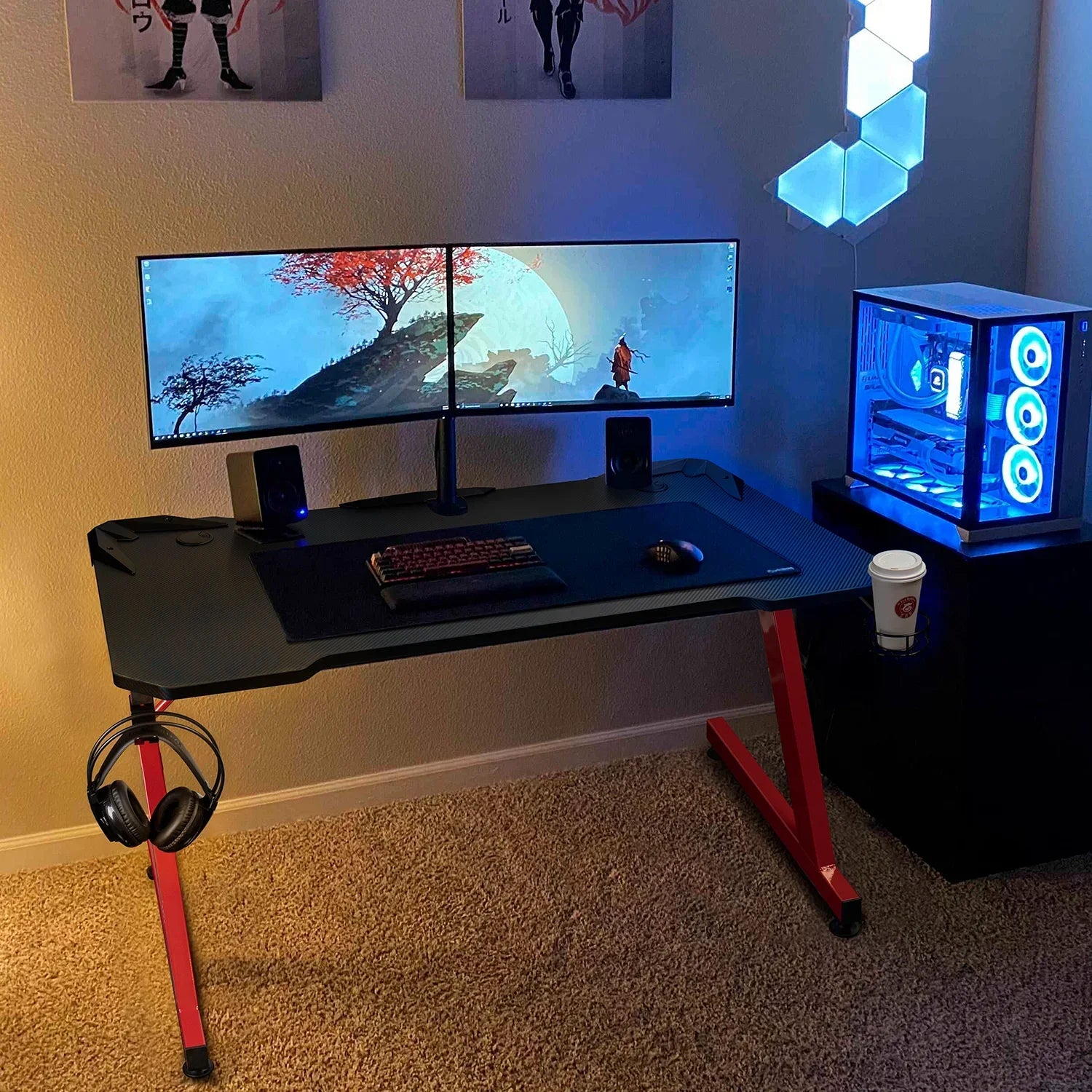 Modern gaming desk setup with dual monitors, RGB-lit PC, mechanical keyboard, mouse, speakers, headphones, and cup holder