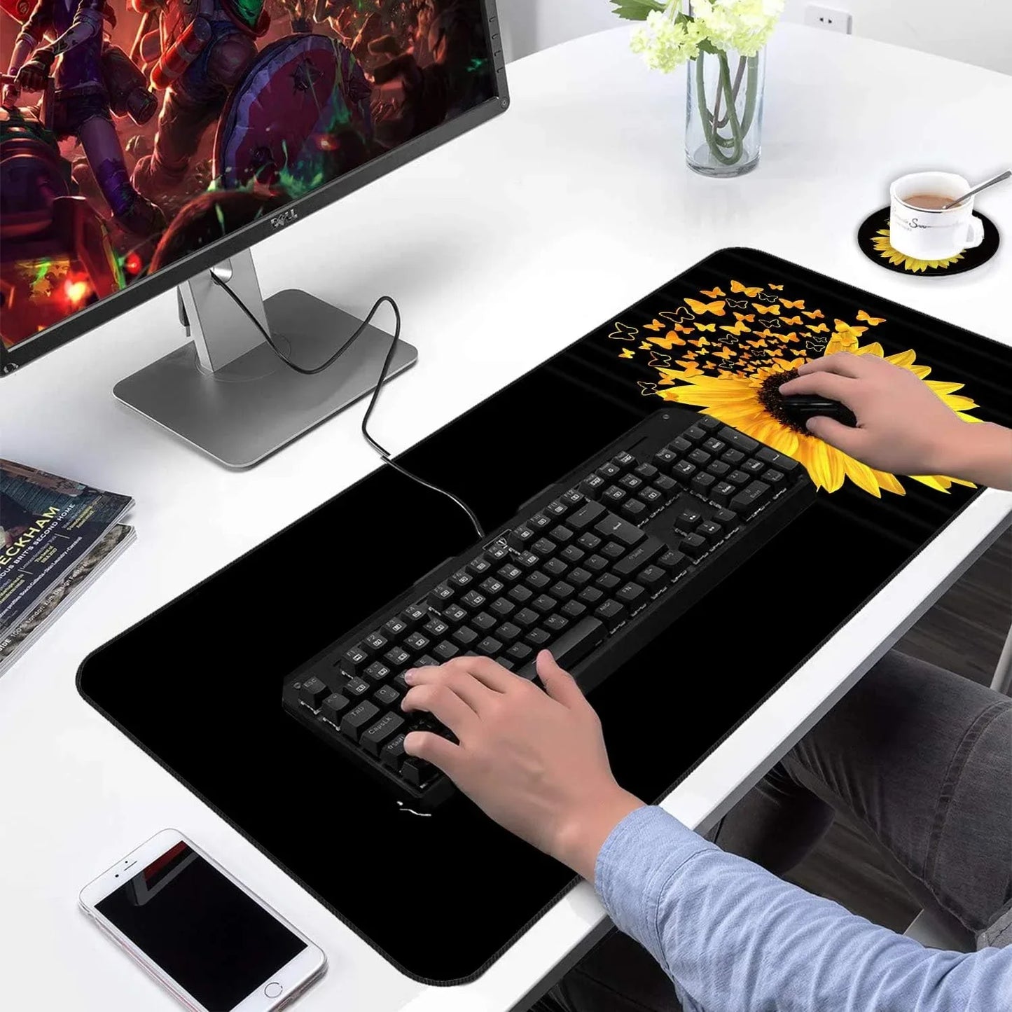 Gaming desk setup with sunflower and butterfly design extended mouse pad, mechanical keyboard, gaming monitor, and smartphone