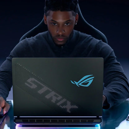 Gamer using ASUS ROG Strix gaming laptop at a desk with RGB lighting