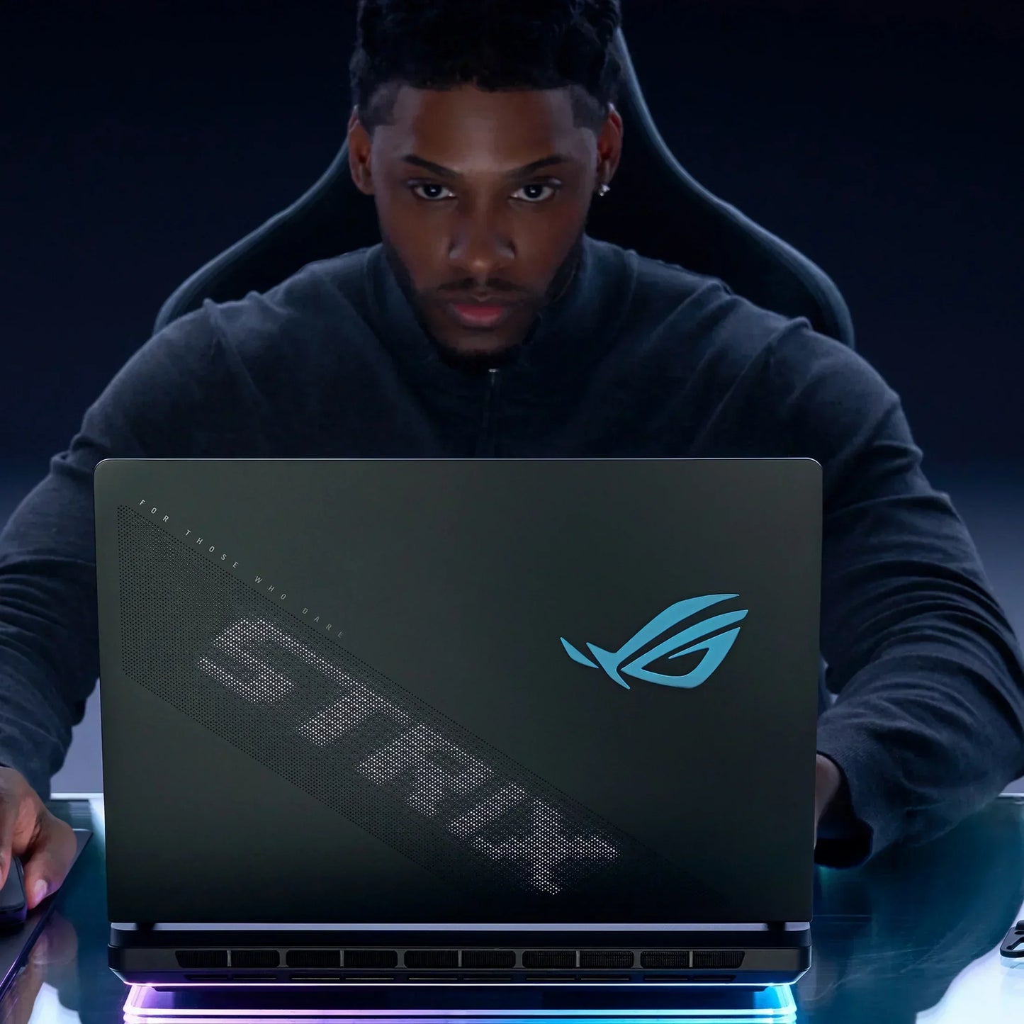 Gamer using ASUS ROG Strix laptop with LED logo in a dark gaming setup