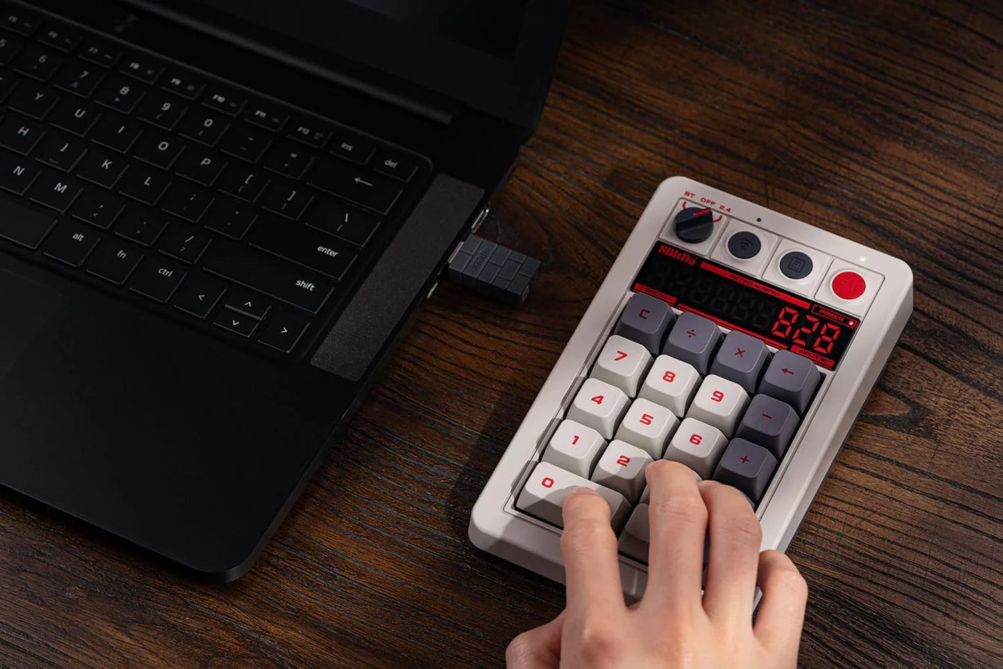 Retro 8-bit style mechanical keypad connected to laptop on wooden desk