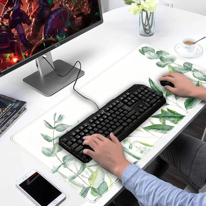 Gaming setup with black wired keyboard, mouse on large leaf-patterned desk mat, monitor displaying game, and white desk