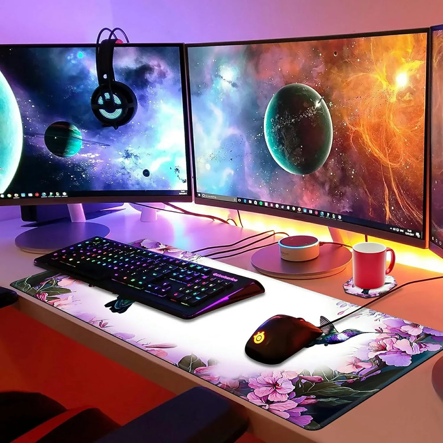 RGB backlit keyboard and gaming mouse on floral desk mat with triple curved space-themed monitors and hanging LED headset