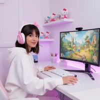 Young woman with pink cat ear headphones gaming on PC with fantasy RPG game on screen in pink-lit room