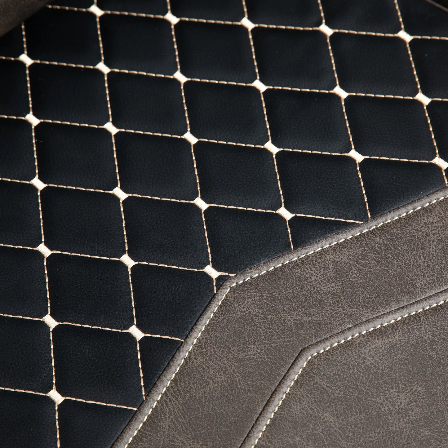 Close-up of black and brown stitched leather texture, showcasing quilted diamond pattern and detailed seams