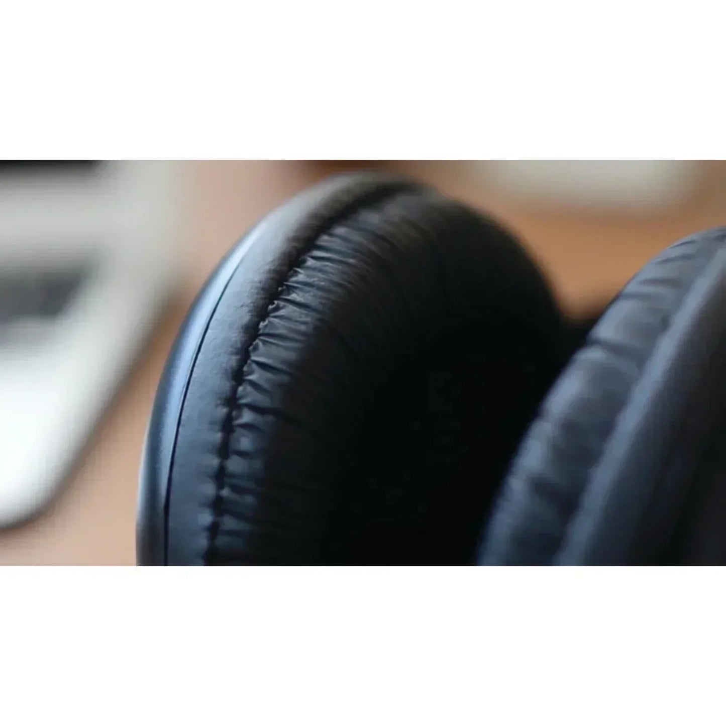 Close-up of black over-ear gaming headset ear cushions on a desk