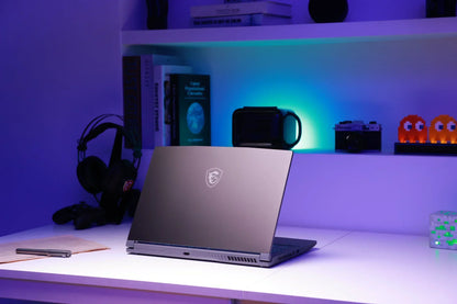 Gaming laptop on a modern desk with RGB lighting, retro 8-bit decor, and accessories