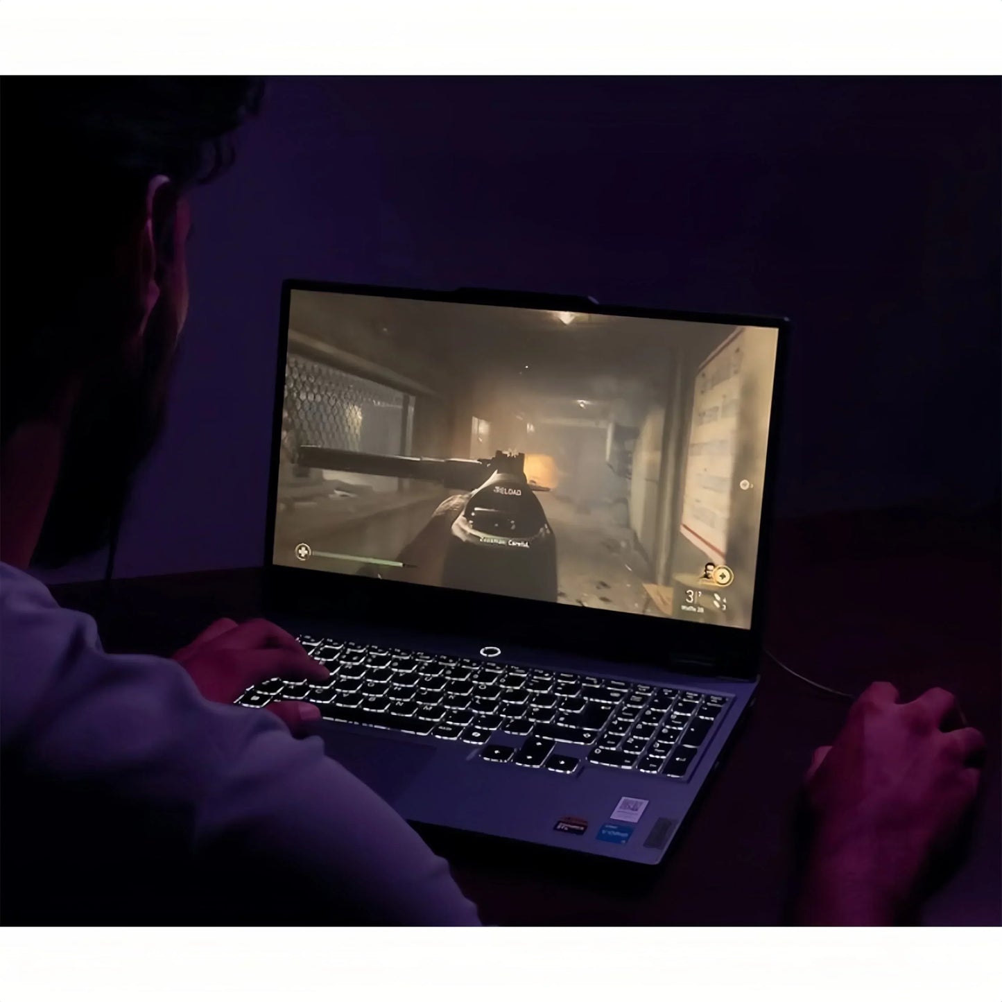 Gamer playing a first-person shooter on a backlit gaming laptop in a dark room