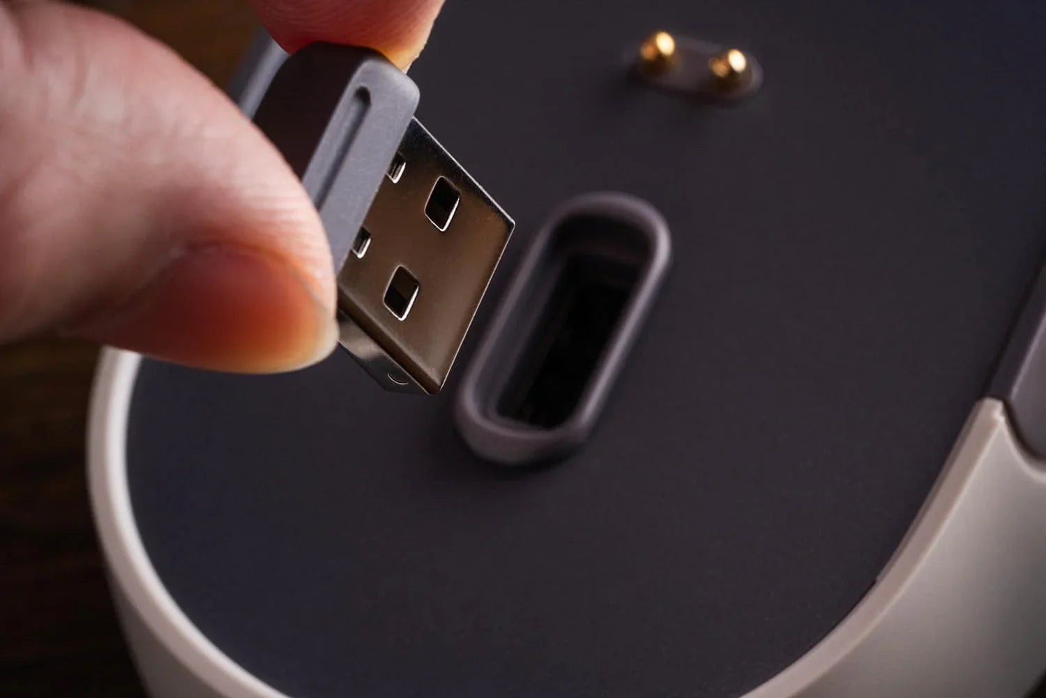 Hand plugging USB receiver into a wireless gaming mouse base