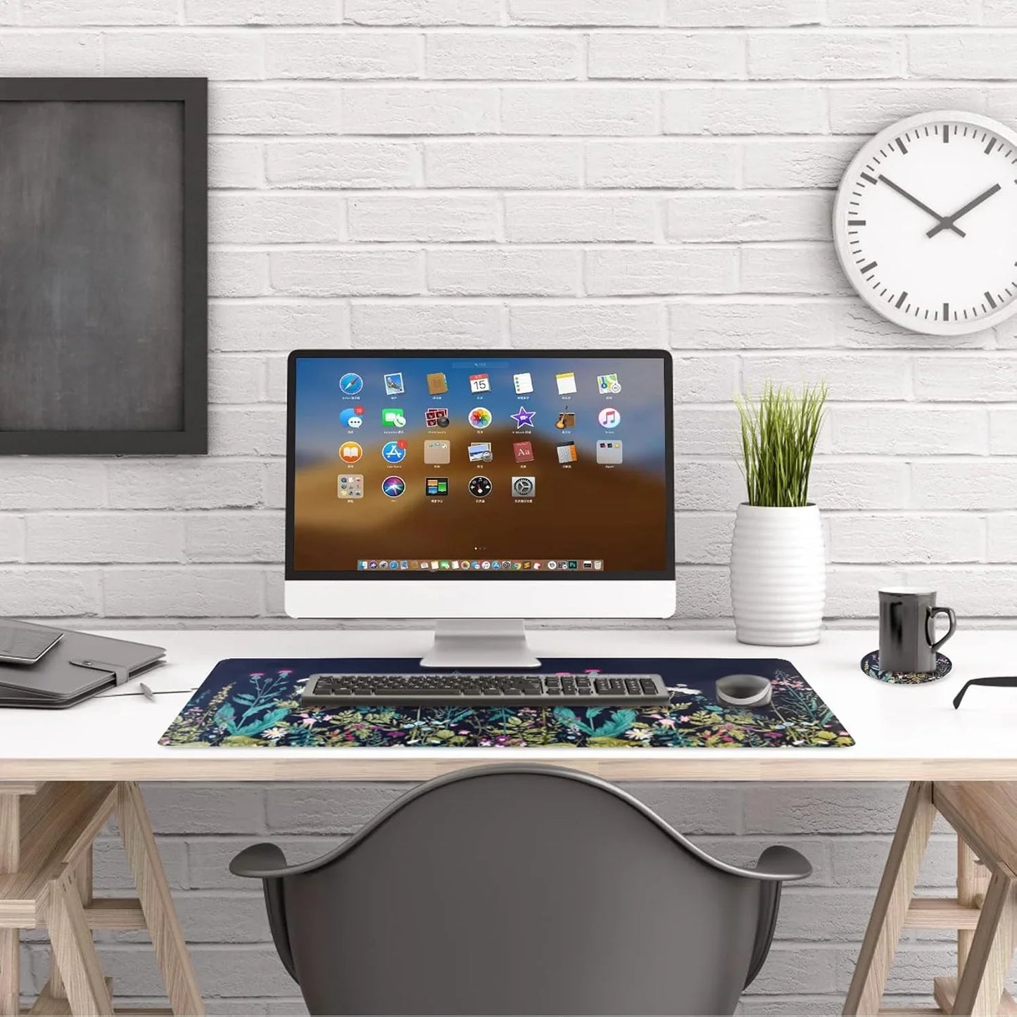 Modern white computer desk setup with all-in-one monitor, floral desk mat, wireless keyboard and mouse, plant, and wall clock