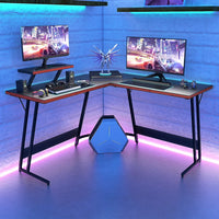 Modern L-shaped gaming desk setup with dual monitors, RGB lighting, model figurine, and gaming accessories