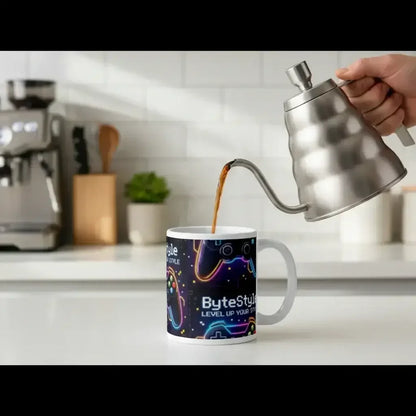 Pouring coffee from stainless steel kettle into video game controller-themed ByteStyle mug on kitchen counter