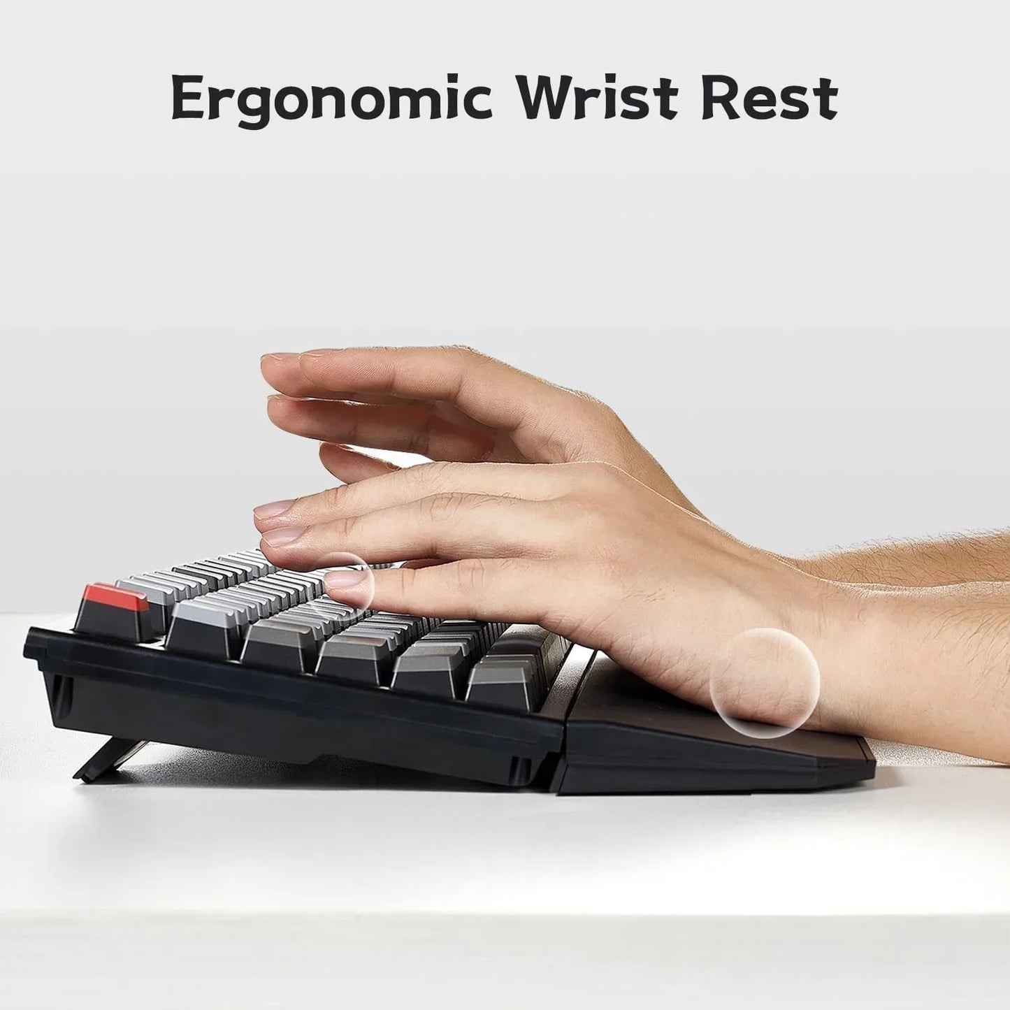 Hand using mechanical gaming keyboard with ergonomic wrist rest, retro 8-bit style setup.