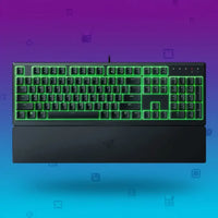 Razer wired mechanical keyboard with green RGB backlighting and black wrist rest on gradient purple-blue background