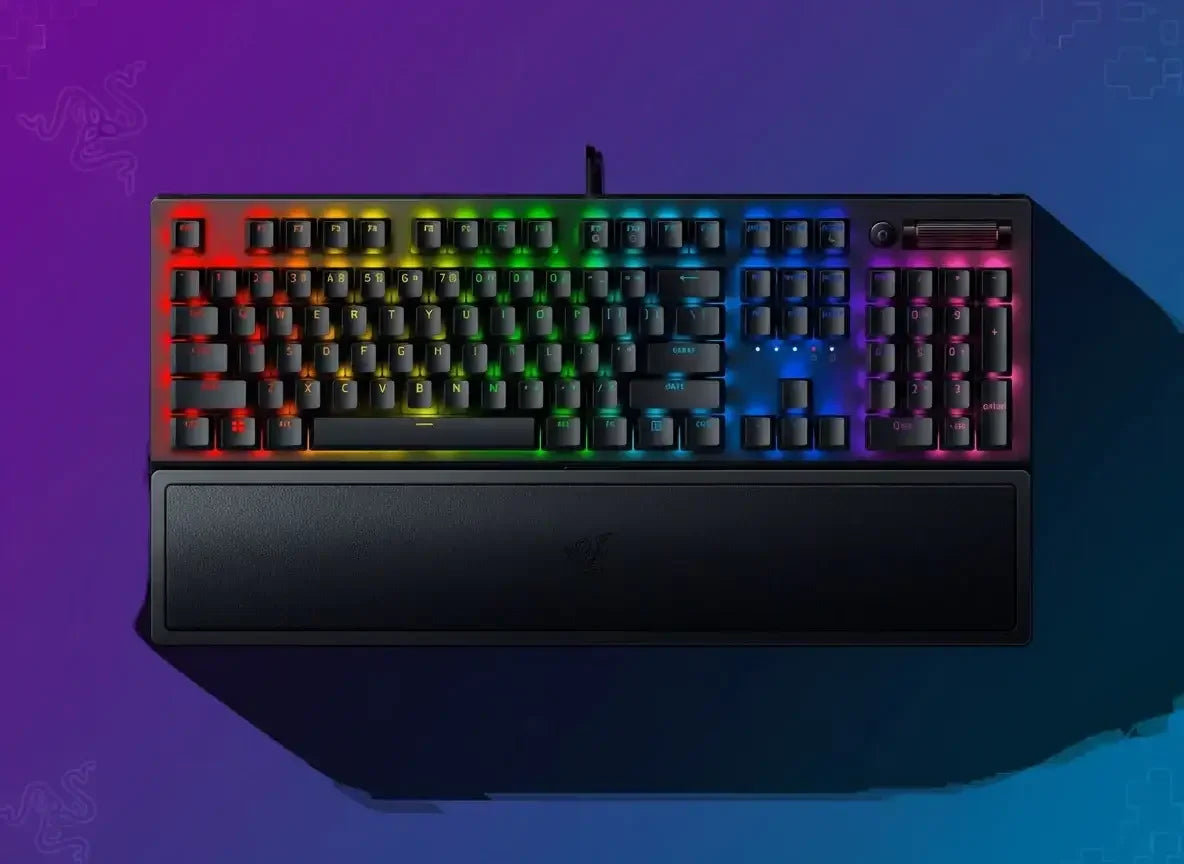 Black gaming keyboard with RGB backlighting and wrist rest on a purple-blue gradient background