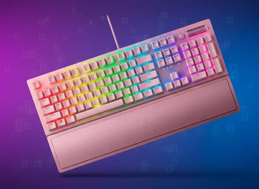White wired mechanical keyboard with rainbow RGB backlighting and pink wrist rest on blue-purple background