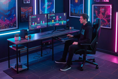 Gamer in hoodie at dual monitor gaming setup with neon lights and pixel art décor