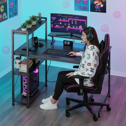 Young woman wearing gaming headset sitting at black L-shaped computer desk with gaming PC and neon-lit monitor displaying retro video game
