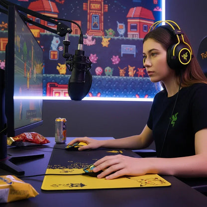 Young woman gaming with Razer headphones, dual mice, and microphone in colorful Pokemon-themed room